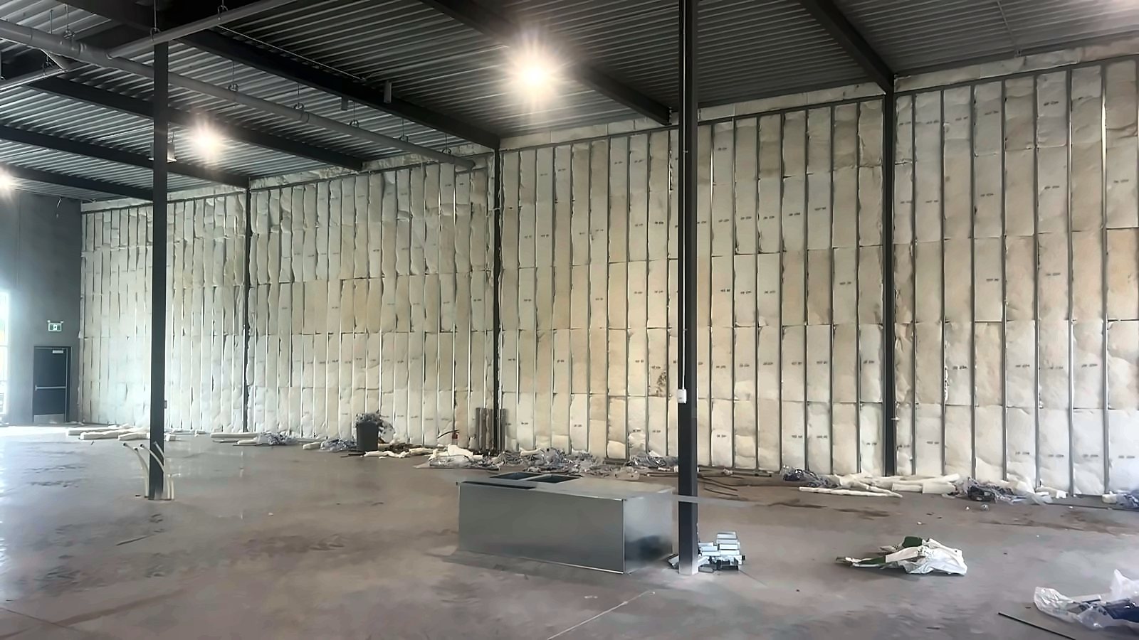 A wide open bay with a full-height insulated steel stud wall and exposed roof deck above